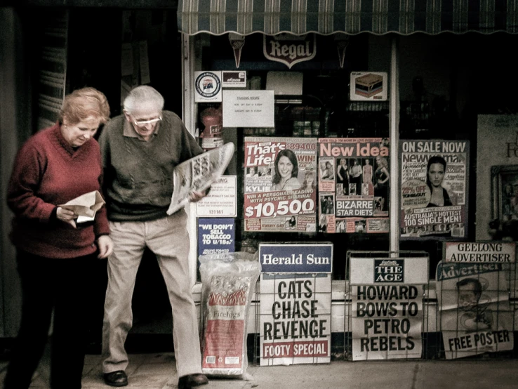 two people looking at newspaper articles in a bookstore window