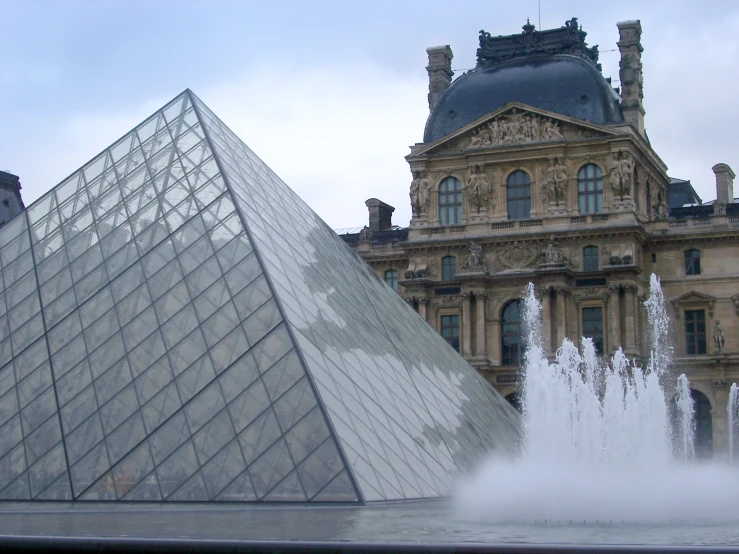 a fountain with water spouting out and the back of a very large building