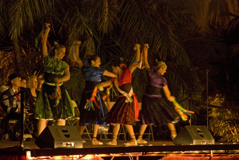 several women on a stage holding their hands up