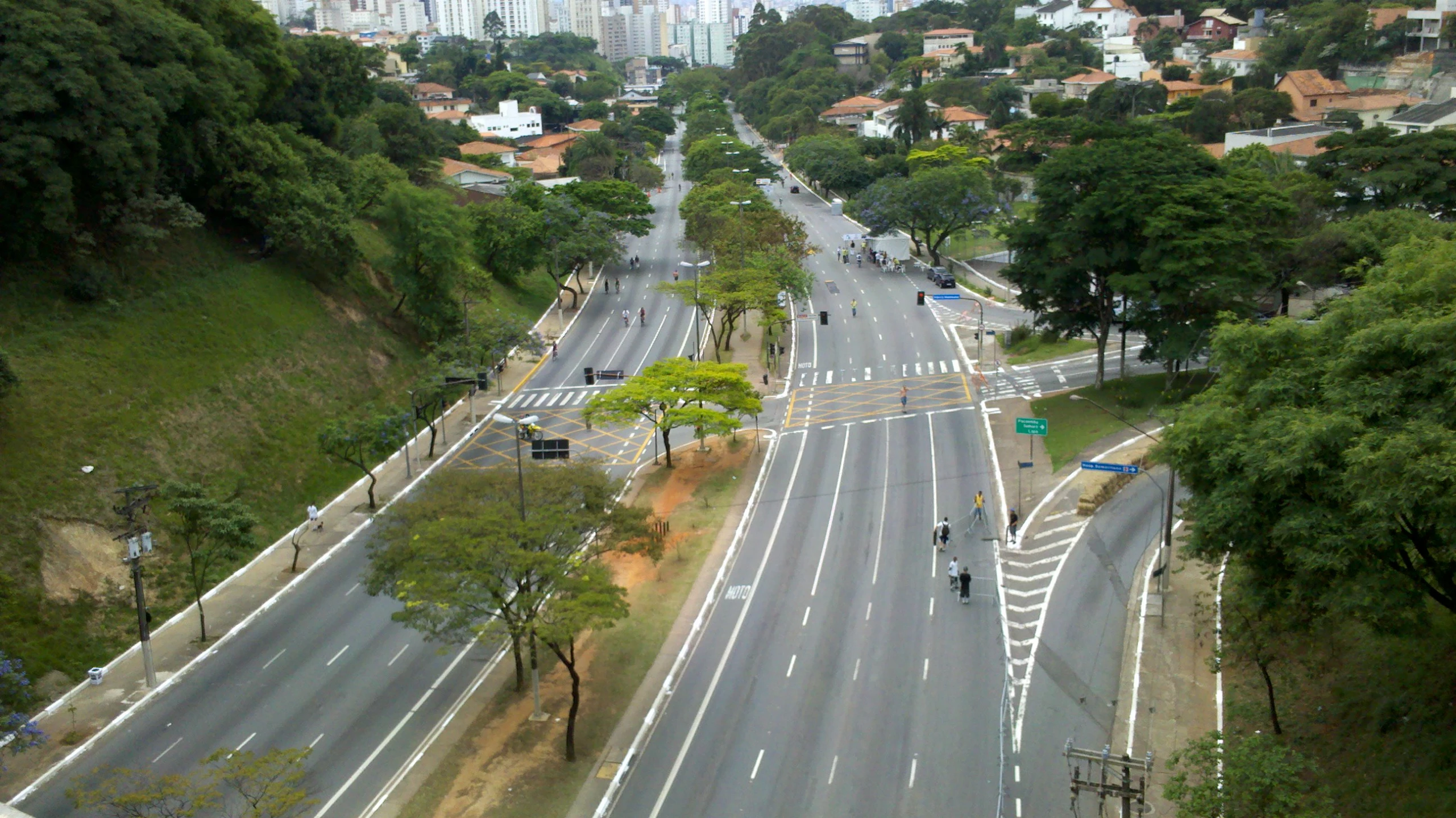 a wide city road surrounded by trees and a hill