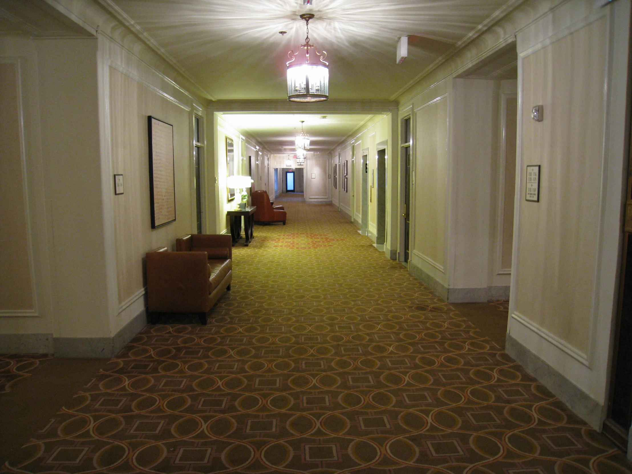 a hallway with a lamp a chair and pictures on the walls