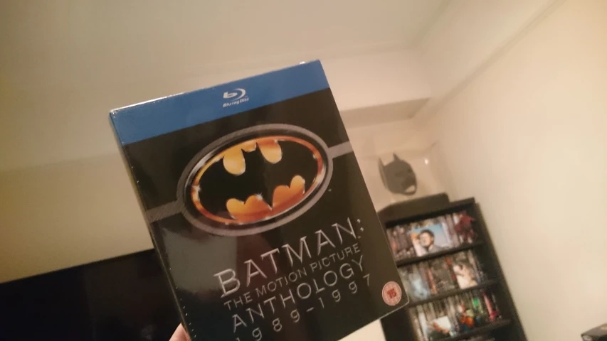 a batman dvd with a person holding the case