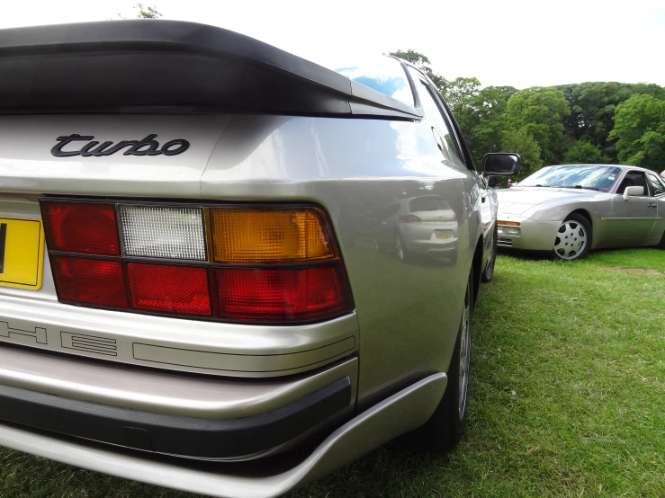 the back of a silver car parked in grass