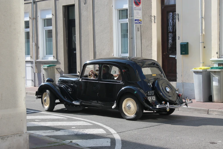 a vintage black car driving down the street