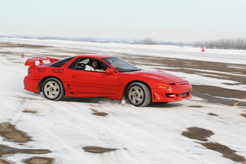 a red car driving along a snowy road