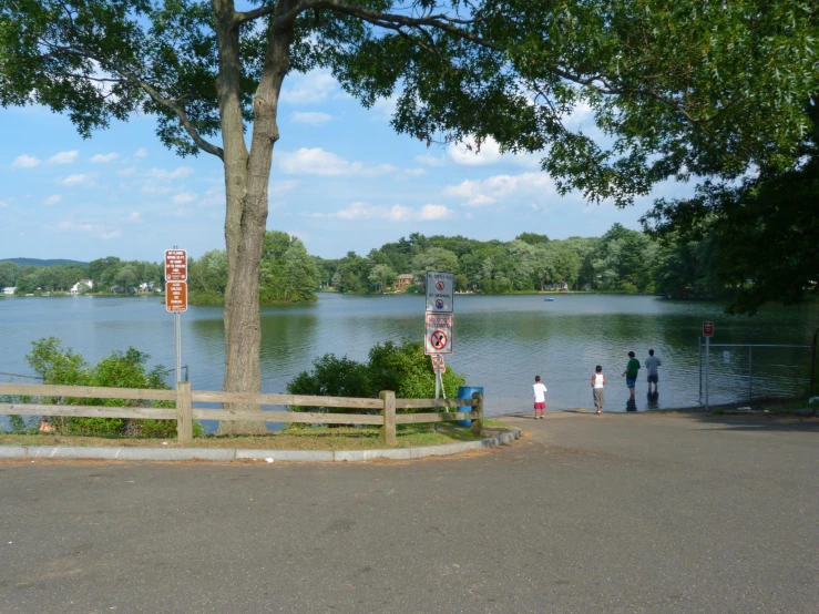 people are standing at the corner by the lake
