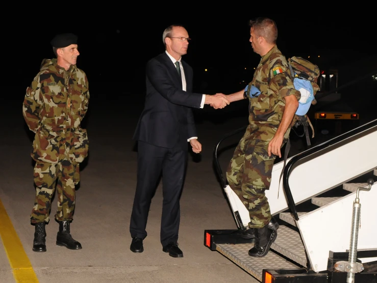 military men are shaking hands as they leave the plane