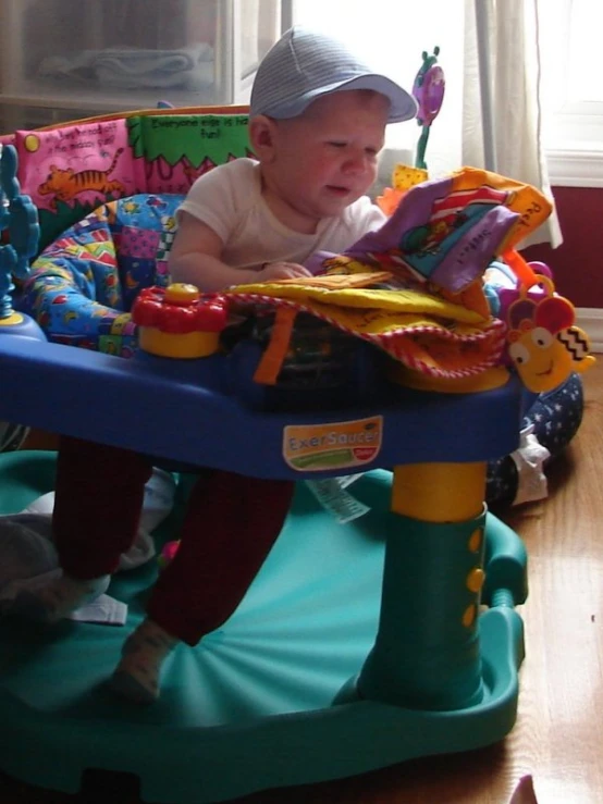 baby sitting in a high chair and looking at his toys