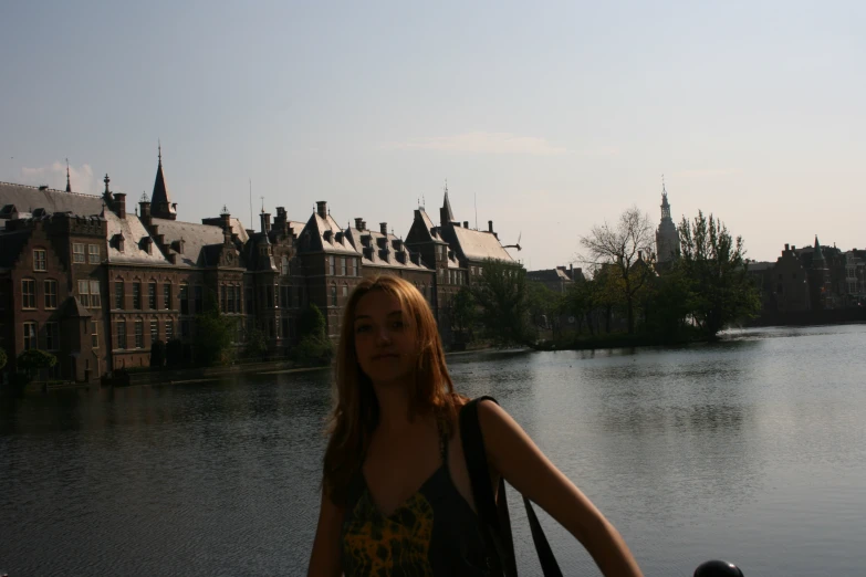 a woman standing next to the water near some buildings
