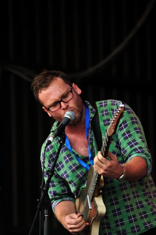 a man singing into a microphone and holding a guitar