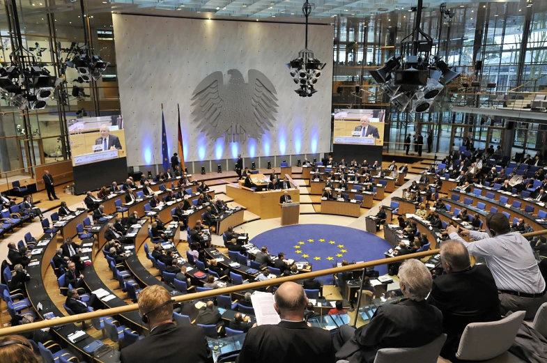 several people sitting at tables and chairs and a big screen