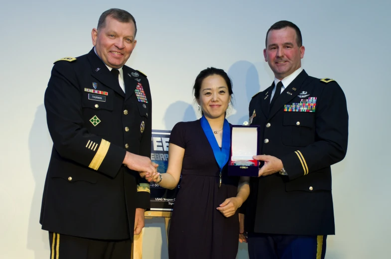 a woman presenting an award to two men