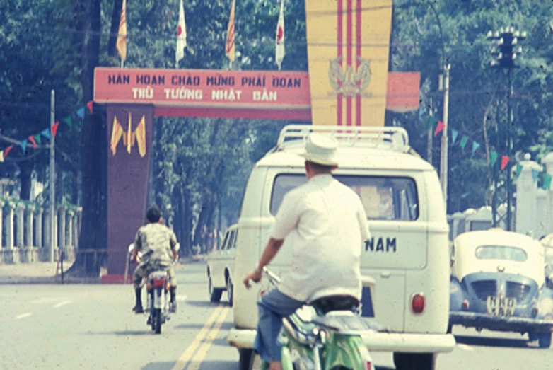 a couple of men riding bikes on a busy street