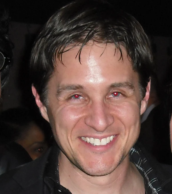 a man wearing a black shirt smiling for the camera