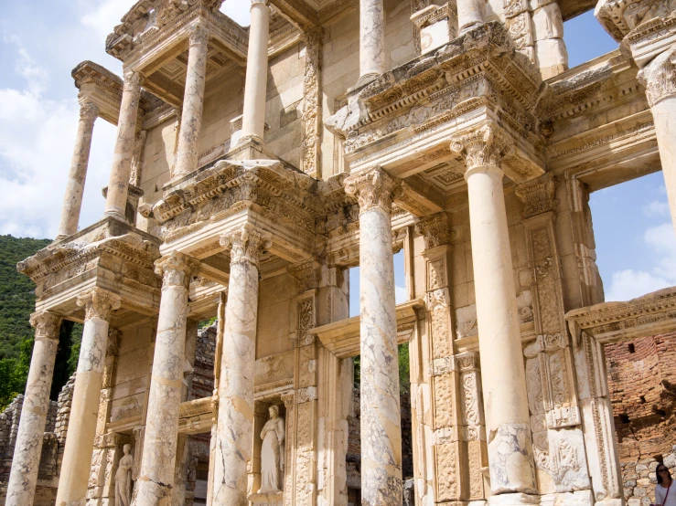 a stone structure with columns and pillars has people looking up