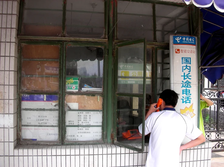 a man standing in front of a store talking on a cell phone