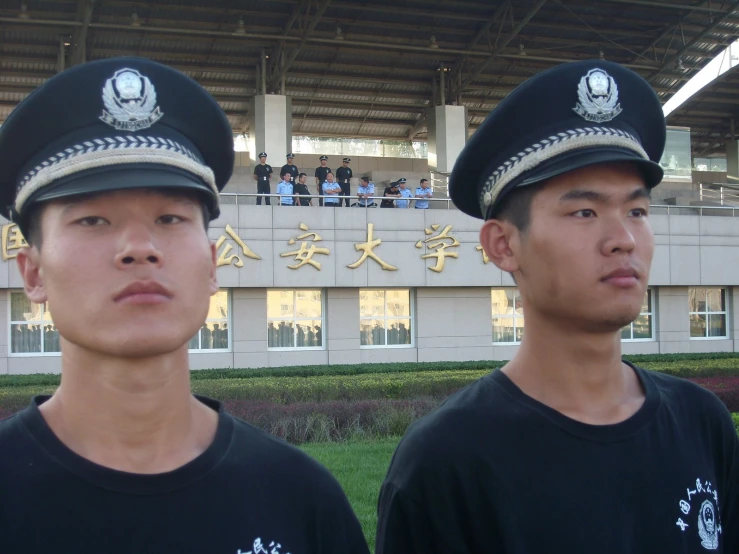 two uniformed men in hats are standing side by side