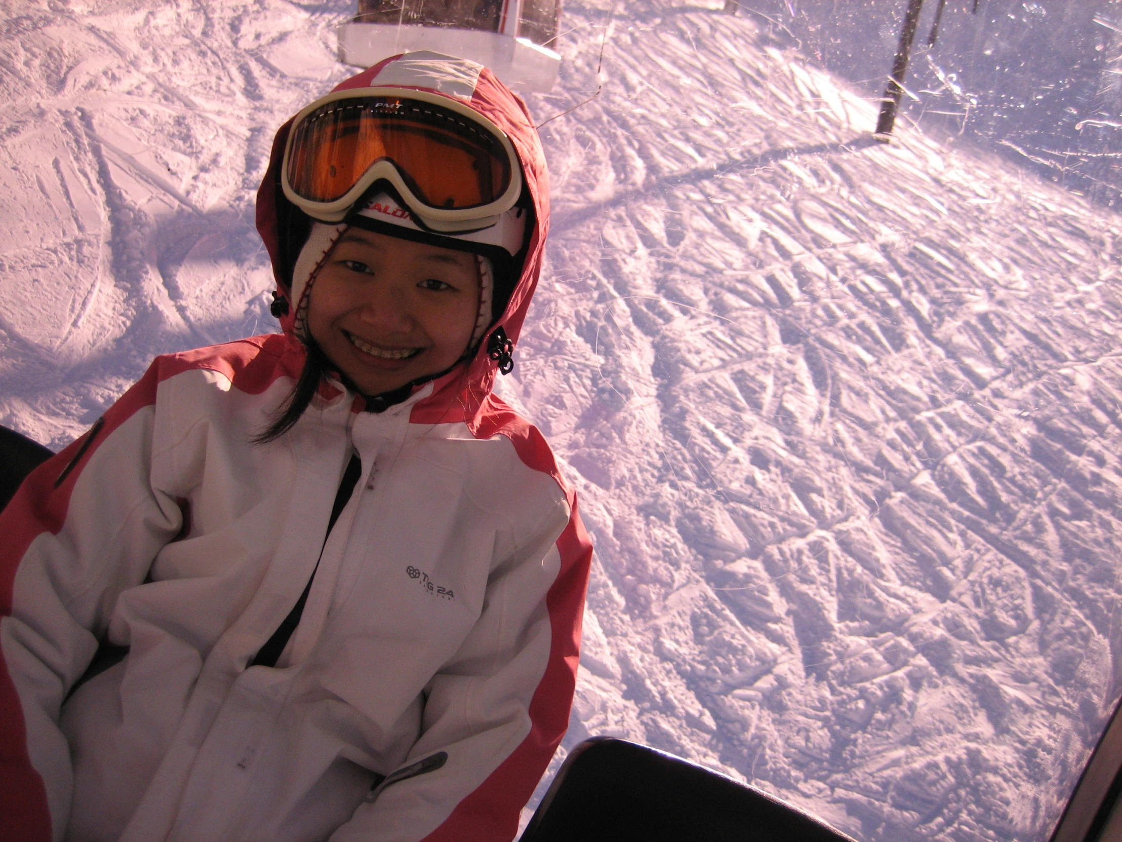 a little girl sitting on top of a snow covered ski slope