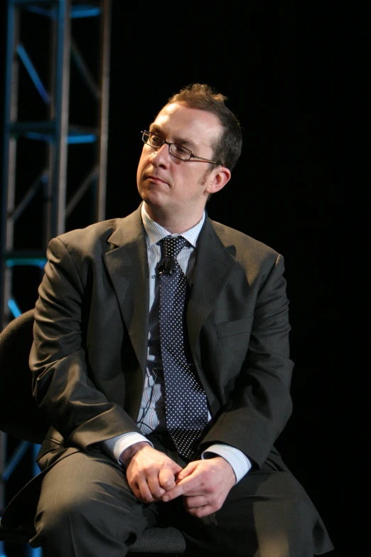 a man in suit sitting and looking forward at soing