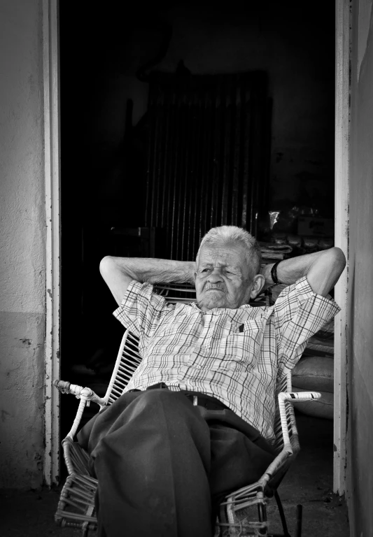 an older man sitting on a lawn chair looking back