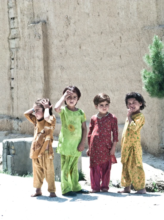 several small children standing in front of an unfinished building