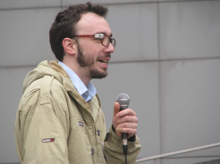 a man wearing glasses standing next to a microphone