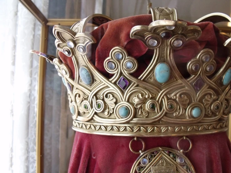 a gold crown with beads hanging on a curtain