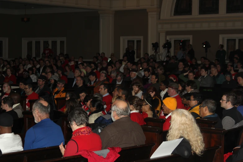 a crowd of people in a auditorium looking down on soing