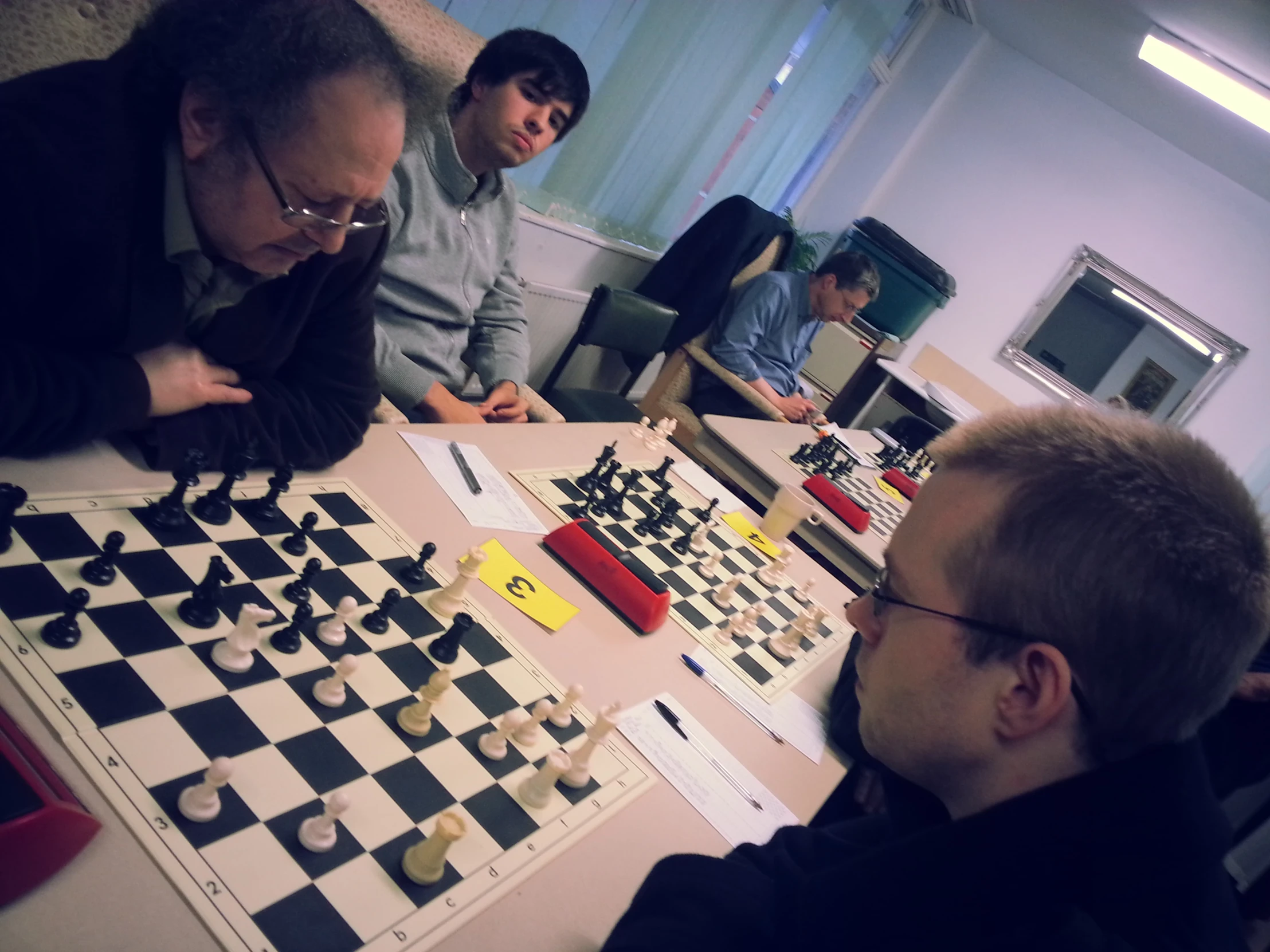 people playing a game of chess with two standing in front of them