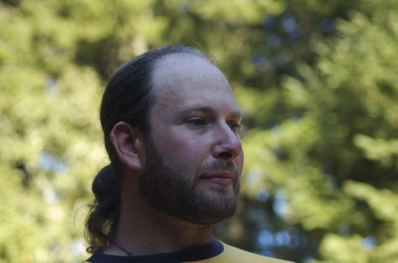 a man with long hair, a beard and a black and yellow shirt