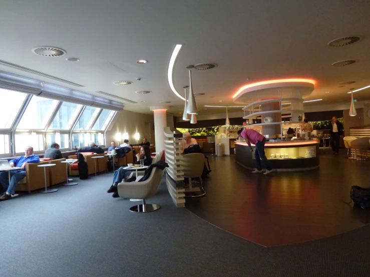 several people sit at tables and drink in a modern building