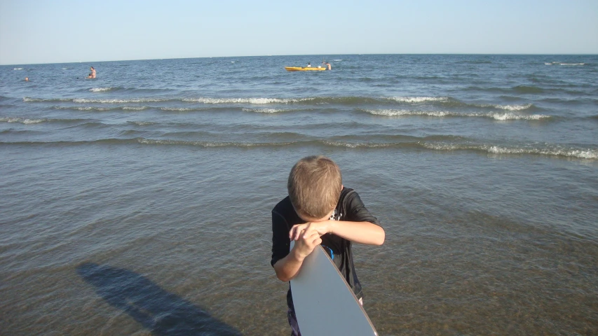 a boy is holding a surf board facing the water