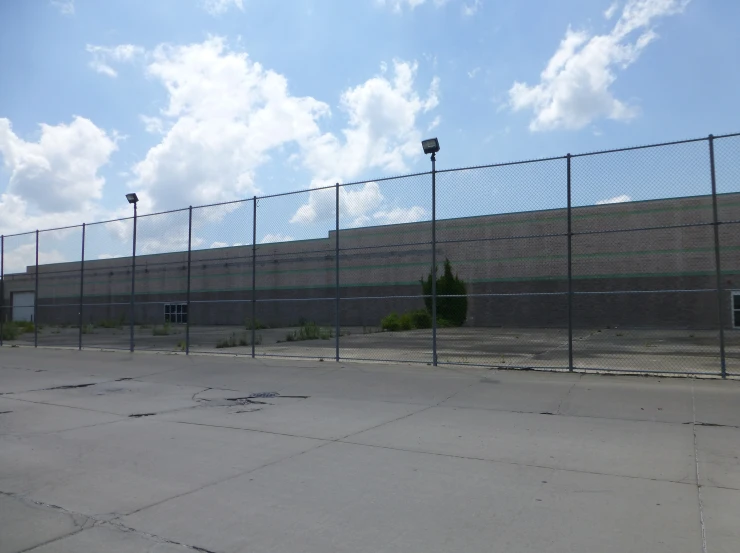 an empty parking lot next to a large fence with no parking spaces