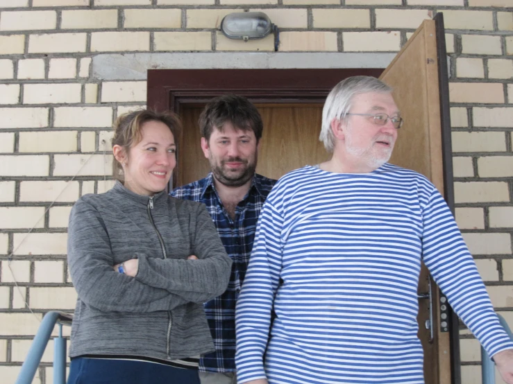 three people stand in a door way while a lady stands on the side of the door and stares at the viewer