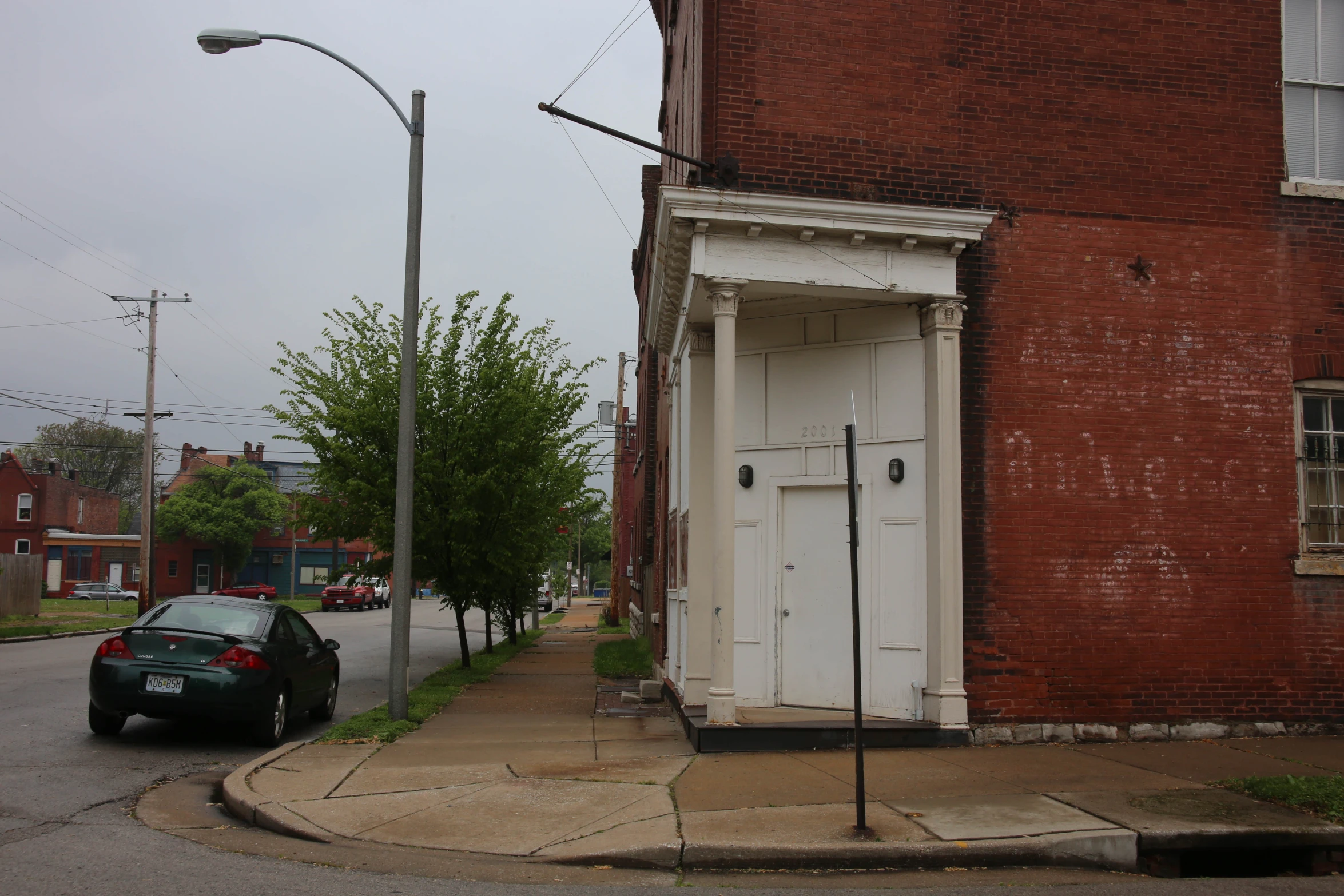 a green car parked in front of a red brick building