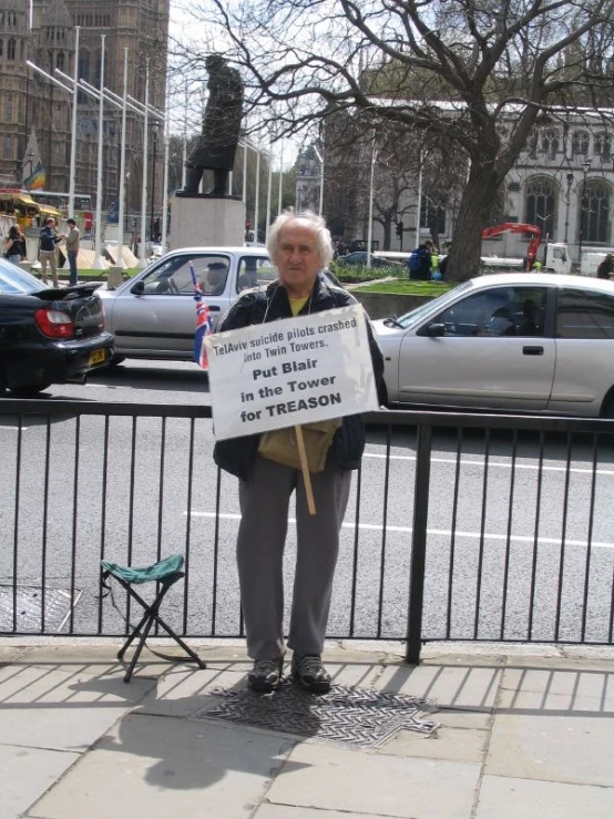 a woman holds up a sign while standing next to a fence