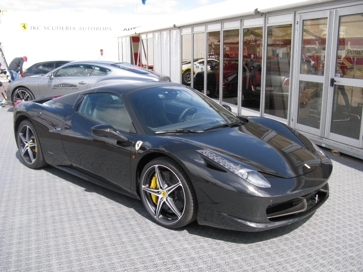 the front view of a dark car is parked outside a showroom