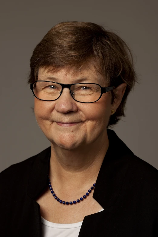 an old woman wearing glasses and a beaded necklace smiles