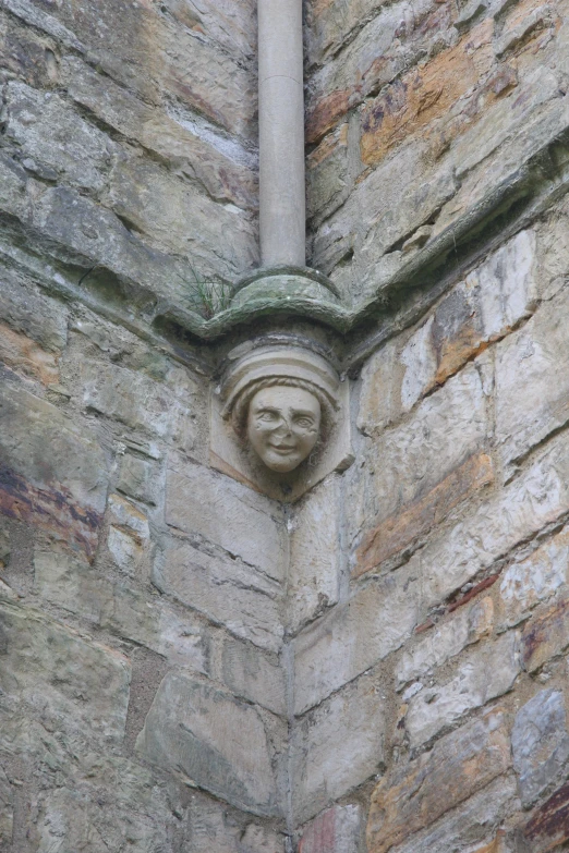 face sculpted into brick wall, with head on post