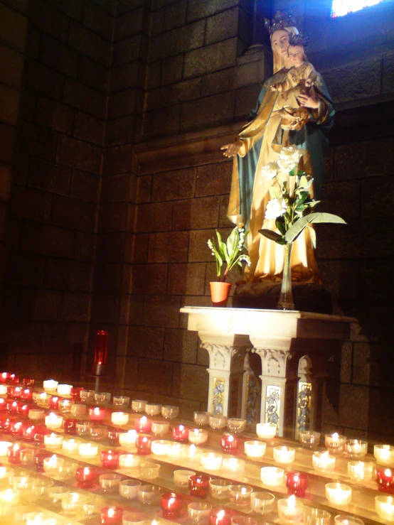 a statue and flowers on a table filled with candles