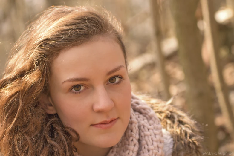 a woman in a scarf looks out from the woods