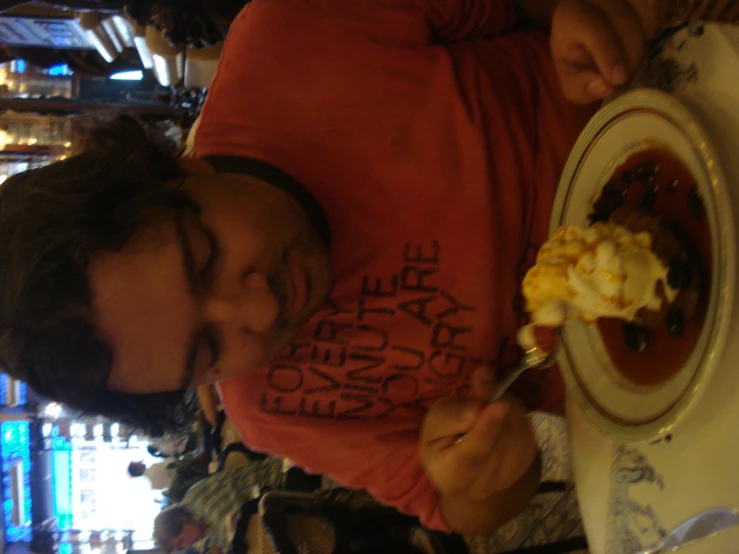 man with red shirt eating food from a plate