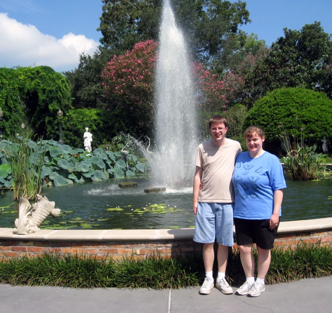 a couple posing for a po with a fountain in the background