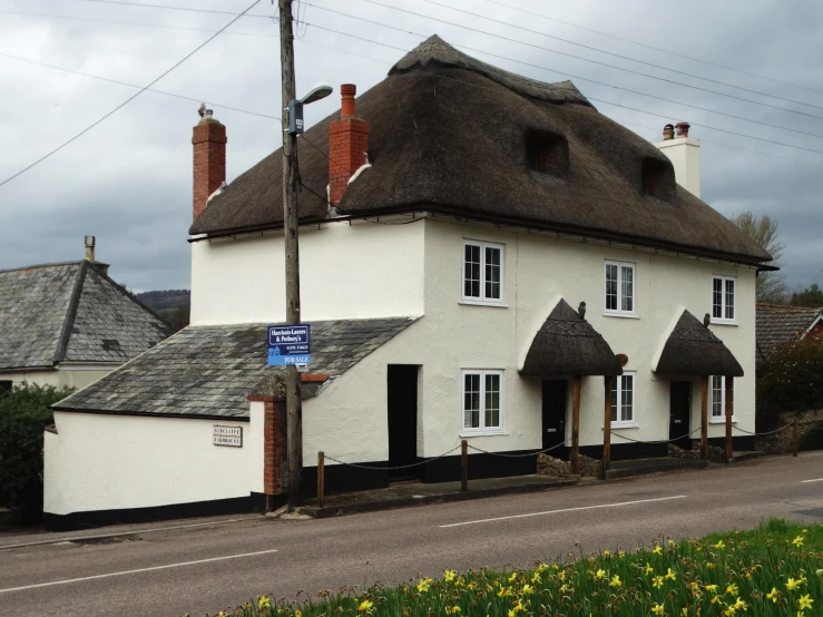 an english style building with a thatched roof and chimneys