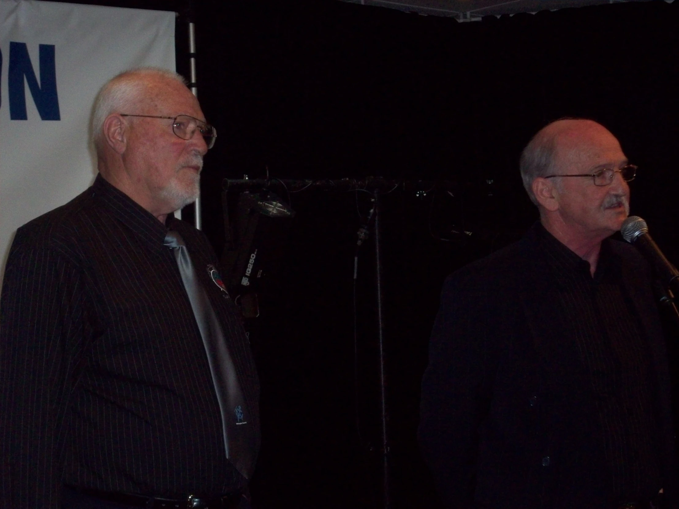 two older men standing in front of a microphone