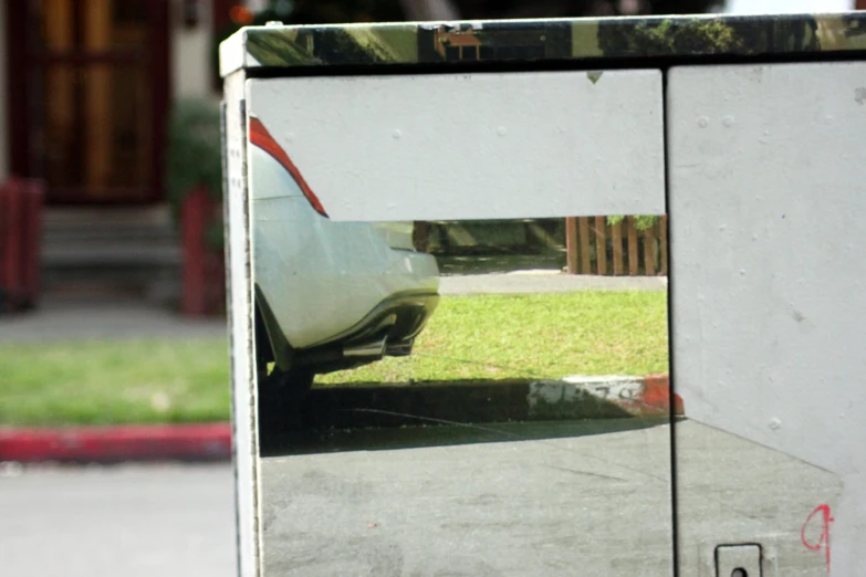 a car sits parked in front of a large mirror
