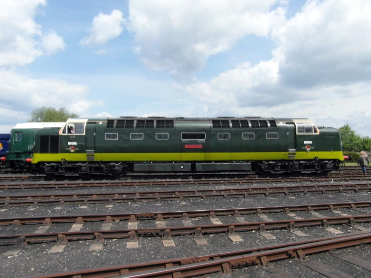 a green train parked on the tracks at a station