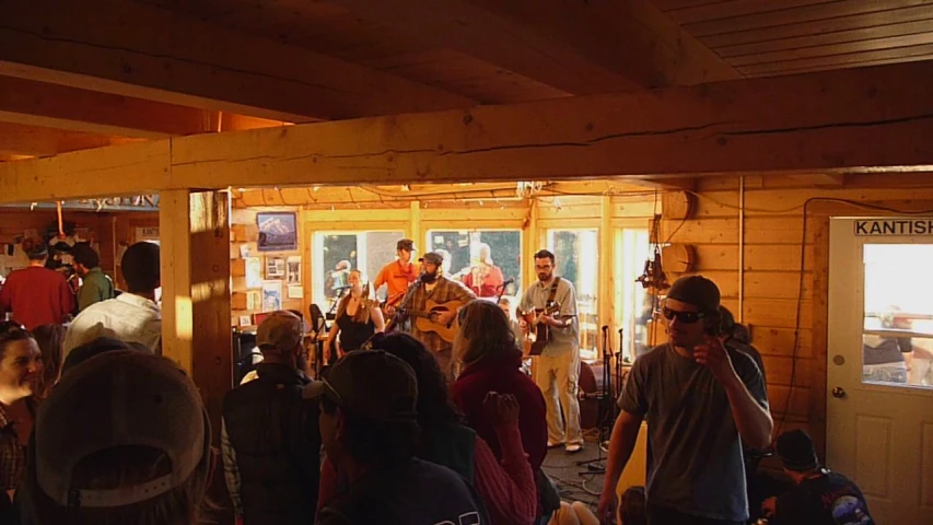 people standing outside an open wooden building watching another group