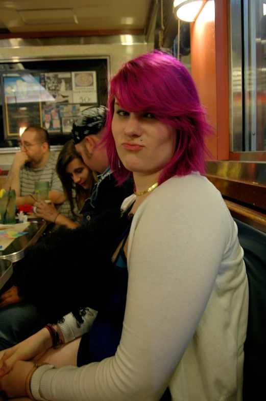 a young lady with pink hair sitting in a restaurant