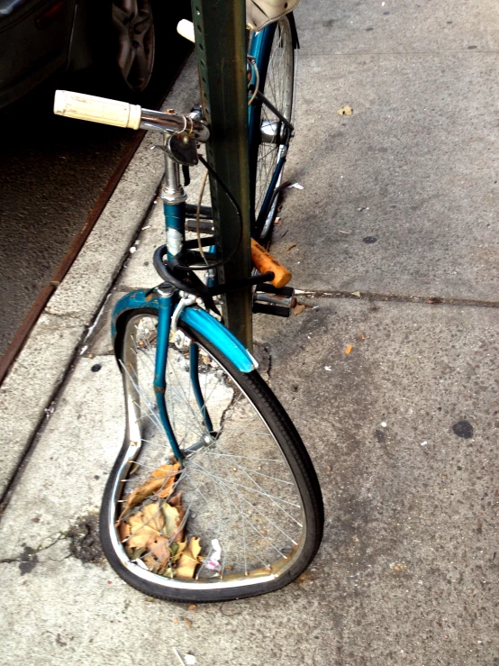 a blue bicycle  to a metal pole